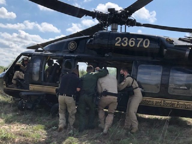 A CBP AMO agent and Border Patrol agents load a distressed migrant woman into a Black Hawk helicopter in Brooks County, Texas. (Photo: CBP Air and Marine Operations/McAllen Air Branch)