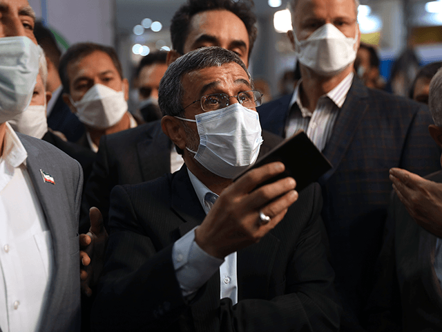 Former President Mahmoud Ahmadinejad listens to journalists while registering his name as