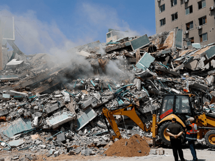 Workers clear the rubble of a building that was destroyed by an Israeli airstrike on Satur