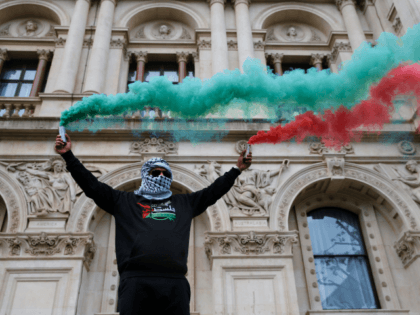 LONDON, ENGLAND - MAY 16: A demonstrator holds green and red smoke flares during a protest