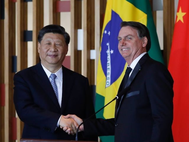 Chinese President Xi Jinping (L) and Brazilian President Jair Bolsonaro shake hands during a press statement after their bilateral meeting at Itamaraty Palace in Brasilia, Brazil, on November 13, 2019. - Brazil's President Jair Bolsonaro walked a diplomatic tightrope, as he seeks to boost ties with Beijing and avoid upsetting …