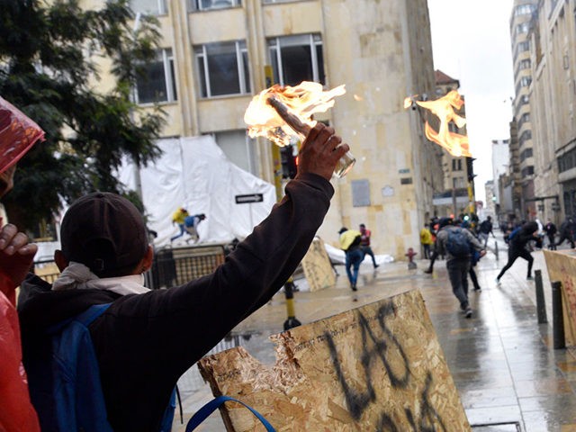 BOGOTA, COLOMBIA - MAY 05: A protester throws a molotov cocktail towards riot police at Bolivar Square during national strike on May 05, 2021 in Bogota, Colombia. Despite that the ruling party announced withdrawal of the unpopular bill for a tax reform and the resignation of the Minister of Finances, …