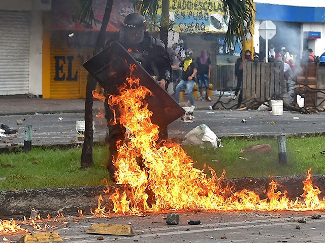 TOPSHOT - A riot police officer got him by a Molotov cocktail thrown during clashes with demonstrators protesting against a tax reform bill launched by President Ivan Duque, despite the president then ordered the proposal be withdrawn from Congress, in Cali, Colombia, on May 3, 2021. - Protesters in Colombia on Monday called for a new mass rally after 19 people died and more than 800 were wounded in clashes during five days of demonstrations against a proposed government tax reform. (Photo by Luis ROBAYO / AFP) (Photo by LUIS ROBAYO/AFP via Getty Images)