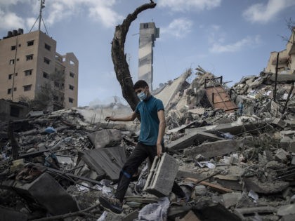 A Palestinian man inspects the damage of a six-story building which was destroyed by an early morning Israeli airstrike, in Gaza City, Tuesday, May 18, 2021. Israel carried out a wave of airstrikes on what it said were militant targets in Gaza, leveling a six-story building in downtown Gaza City, …