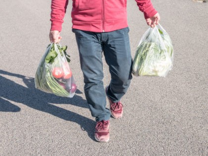 Male holding a plastic bag of vegetables