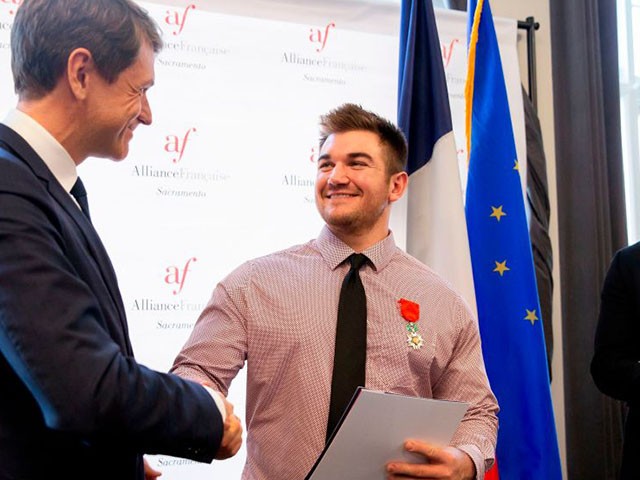 American Alek Skarlatos (C) shakes hands with Emmanuel Lebrun-Damiens, French Consul General in San Francisco, after being given his naturalization certificate during a ceremony at the Alliance Francaise in Sacramento, California, January 31, 2019. - American citizens Anthony Sadler, Alek Skarlatos and Spencer Stone received honorary French citizenship after foiling a terror attack in 2015 on a high-speed train en route to Paris from Amsterdam when a gunman aboard the train opened fire. (Photo by Brittany Hosea-Small / AFP) (Photo credit should read BRITTANY HOSEA-SMALL/AFP via Getty Images)
