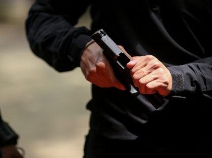 Details with the hands of a man handling a 9 mm handgun
