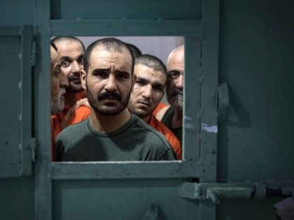 Men, suspected of being affiliated with the Islamic State (IS) group, look out of the opening of a prison cell in the northeastern Syrian city of Hasakeh on October 26, 2019. - Kurdish sources say around 12,000 IS fighters including Syrians, Iraqis as well as foreigners from 54 countries are …