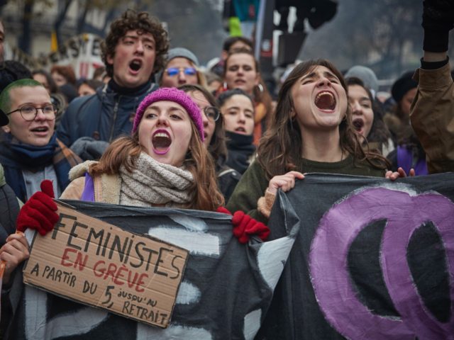 PARIS, FRANCE - DECEMBER 05: Feminist protestors chant and sing songs against President Macron during a rally near Place de Republique in support of the national strike in France, one of the largest nationwide strikes in years, on December 05, 2019 in Paris, France. President Emmanuel Macron is facing his …