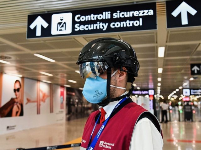 A Fiumicino airport employee wearing a "Smart-Helmet" portable thermoscanner to screen passengers and staff for COVID-19, stands prepared at boarding gates on May 5, 2020 at Rome's Fiumicino airport during the country's lockdown aimed at curbing the spread of the COVID-19 infection, caused by the novel coronavirus. (Photo by ANDREAS …