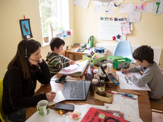 Six-year-old Leo (R) and his three-year old brother Espen (C) complete homeschooling activities suggested by the online learning website of their infant school, as his mother Moira, an employee of a regional council, works from home in the village of Marsden, near Huddersfield, northern England on May 15, 2020, during …