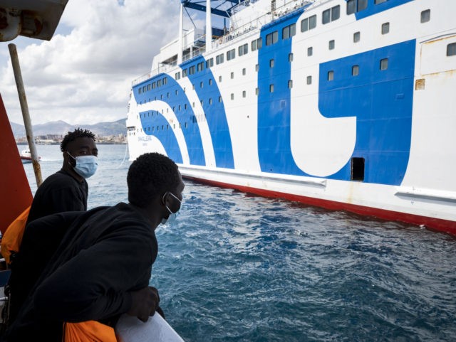 Two migrants ob board the Sea-Watch 4 civil sea rescue ship look on as they approach a ferry at sea off the coast of Palermo, Sicily, Italy, on September 02, 2020, in order to disembark some 350 migrants who will be under quarantine. - More than 350 migrants including those …