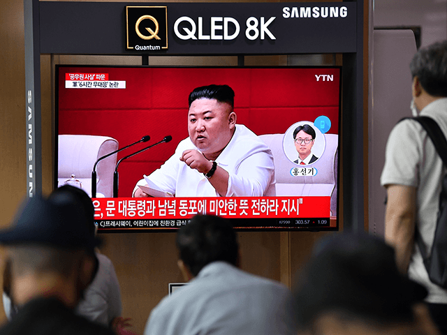 People watch a television news broadcast showing file footage of North Korean leader Kim J