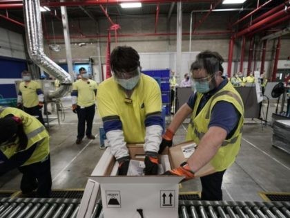 Workers pack boxes containing the Pfizer-BioNTech Covid-19 vaccine as they are prepared to