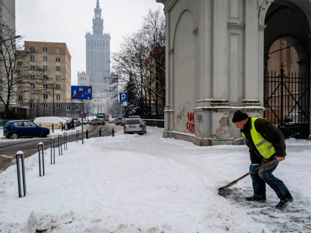 A municipal worker clears the sidewalk from snow in the center of Warsaw, February 10, 202