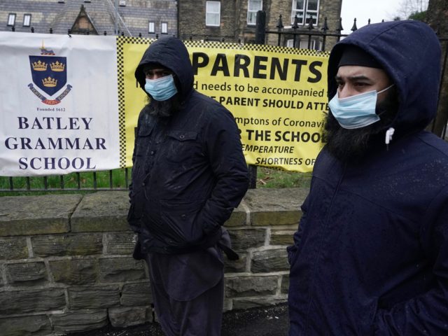 BATLEY, ENGLAND - MARCH 26: People gather outside the gates of Batley Grammar School, after a teacher was suspended for showing an image of the Prophet Muhammad in class, on March 26, 2021 in Batley, England. A few dozen people, including parents of students, gathered outside the school gates yesterday …