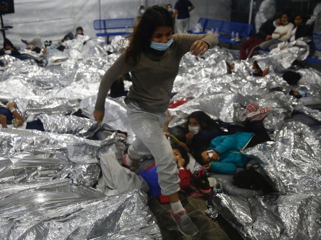 A young female minor walks over others as they lie inside a pod for females at the Donna Department of Homeland Security holding facility, the main detention center for unaccompanied children in the Rio Grande Valley run by the US Customs and Border Protection, ( CBP), in Donna, Texas Tuesday, …