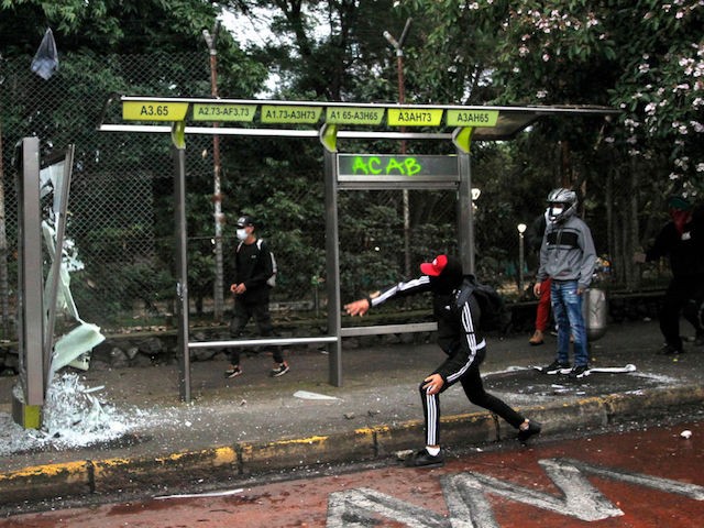 MEDELLIN, COLOMBIA - MAY 05: A demonstrator throws a rock into a bus stop shattering a glass panel during national strike on May 5, 2021 in Medellin, Colombia. Despite that the ruling party announced withdrawal of the unpopular bill for a tax reform and the resignation of the Minister of Finances, social unrest continues after a week. The United Nations human rights office (OHCHR) showed its concern and condemned the riot police repression. Ongoing protests take place in major cities since April 28. (Photo by Fredy Builes/Getty Images)