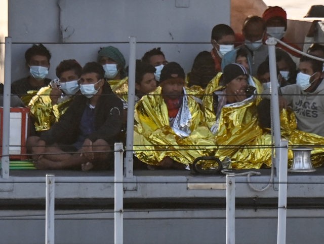 Migrants warmed by emergency blankets arrive on a boat of the Italian Guardia Di Finanza l