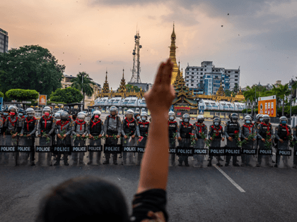 A protester makes a three-finger salute in front of a row of riot police, who are holding roses given to them by protesters, on February 06, 2021 in Yangon, Myanmar. Myanmar's military junta on Saturday placed heavy restrictions on internet connections and suspended more social media services, almost a week …