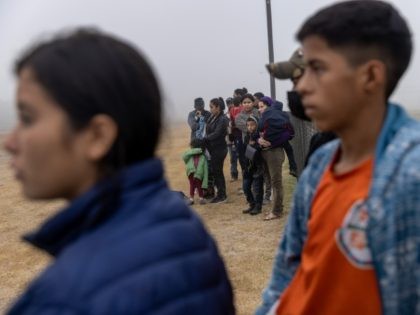 LA JOYA, TEXAS - APRIL 10: Unaccompanied minors (in foreground), stand apart from families waiting to be processed by U.S. Border Patrol agents near the U.S.-Mexico border on April 10, 2021 in La Joya, Texas. A surge of immigrants crossing into the United States, including record numbers of children, continues …