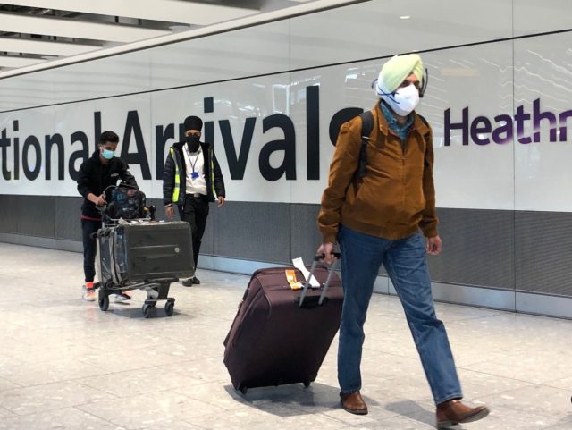 LONDON, ENGLAND - APRIL 23: Passengers are escorted through the arrivals area of terminal 5 towards coaches destined for quarantine hotels, after landing at Heathrow airport on April 23, 2021 in London, England. From 4am this morning, passengers landing in the UK from India are now required to stay in …