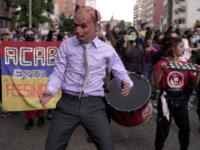 BOGOTA, COLOMBIA - MAY 04: A demonstrator wearing a pig maskperforms with the image of President Duque as a pig during a protest against the government of President Ivan Duque on May 04, 2021 in Bogota, Colombia. Violent clashes between protestors and riot police continue after President Duque ordered Congress …
