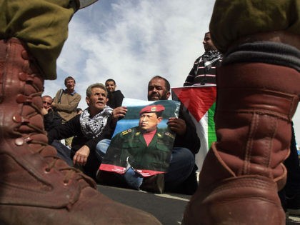 A Palestinian protestor holds a picture of late Venezuelan President Hugo Chavez during a weekly demonstration against Israeli occupation in the West Bank village of Maasarah near Bethlehem on March 8, 2013. Palestinians in Gaza and the West Bank were united in grief over the death of Venezuela's Hugo Chavez, …