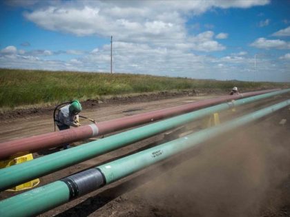 WILLISTON, ND - JULY 25: A construction worker specializing in pipe-laying sandblasts a section of pipeline on July 25, 2013 outside Watford City, North Dakota. North Dakota is currently experiencing an oil boom, creating thousands of jobs throughout the state and billions of dollars in new state revenue. Local two-lane …