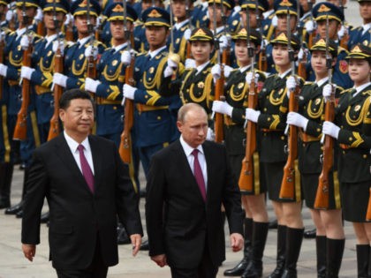 TOPSHOT - Russia's President Vladimir Putin (C) reviews a military honour guard with Chine