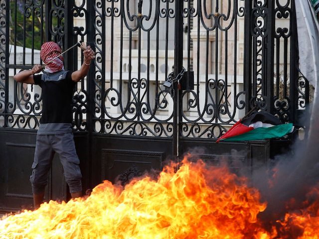 A Palestinian demonstrator hurls rocks at Israeli troops during a fiery confrontation in B