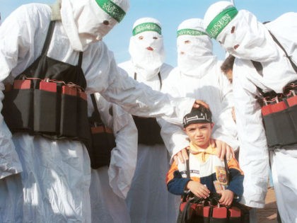 Palestinians dressed as suicide bombers, put fake explosives on a small child December 9, 2001 after marching in commemoration of the 14th anniversary of the Palestinian militant group, Hamas, in Ain El Helweh, the largest Palestinian refugee camp in Lebanon. The camp is home to more than 40,000 Palestinian refugees …