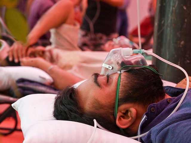 A Covid-19 coronavirus patient breathes with the help of oxygen provided by a Gurdwara, a place of worship for Sikhs, under a tent installed along the roadside in Ghaziabad on May 6, 2021. (Photo by Prakash SINGH / AFP) (Photo by PRAKASH SINGH/AFP via Getty Images)