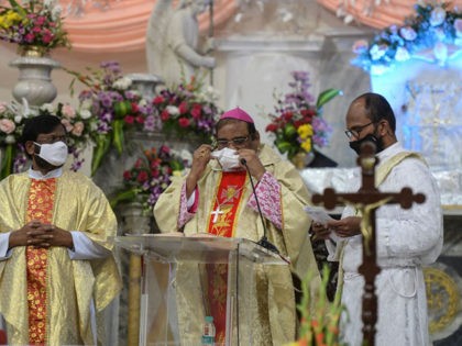 Archbishop of Hyderabad Poola Anthony (C) wears a facemask during the evening mass of the