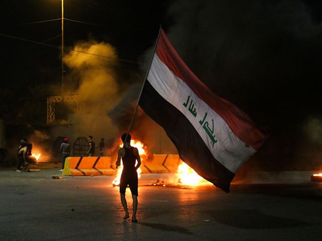 TOPSHOT - Iraqi protesters burn tyres in front of the Karbala governorate headquarters in