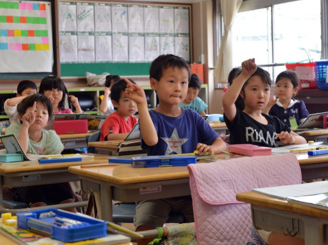 Six-year-old Japanese elemetary student Seishi Nishida (C) raises his hand along with classmates at school in Tokyo on June 11, 2013. AFP PHOTO / Yoshikazu TSUNO (Photo credit should read YOSHIKAZU TSUNO/AFP via Getty Images)