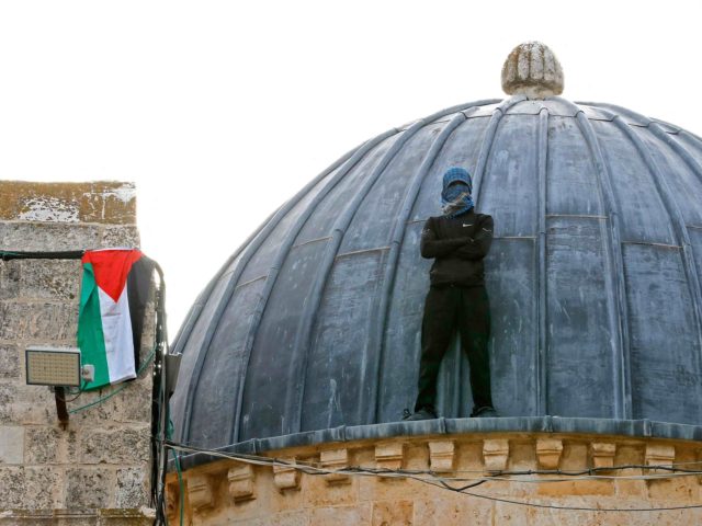 A Palestinian protester stands atop Al-Aqsa mosque in Jerusalem on May 10, 2021, ahead of a planned march to commemorate Israel's takeover of Jerusalem in the 1967 Six-Day War. (Photo by Ahmad GHARABLI / AFP) (Photo by AHMAD GHARABLI/AFP via Getty Images)