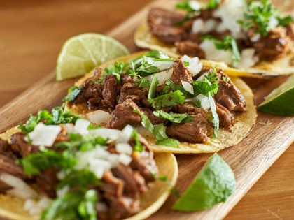 three carne asada mexican street tacos in corn tortilla with lime close up