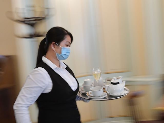 A waitress carries a tray at cafe Einstein in Berlin on May 15, 2020, as lockdown measures were eased and cafes and restaurants were allowed to reopen amid the novel coronavirus / COVID-19 pandemic. (Photo by Tobias SCHWARZ / AFP) (Photo by TOBIAS SCHWARZ/AFP via Getty Images)