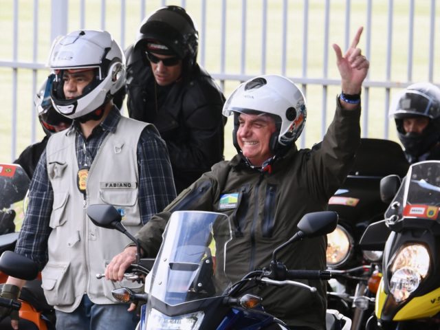 Brazil's President Jair Bolsonaro waves to supporters as he rides a motorcycle leading a c