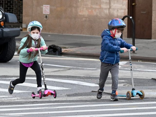 NEW YORK, NY - APRIL 25: Children wearing face masks play on their scooters during the cor