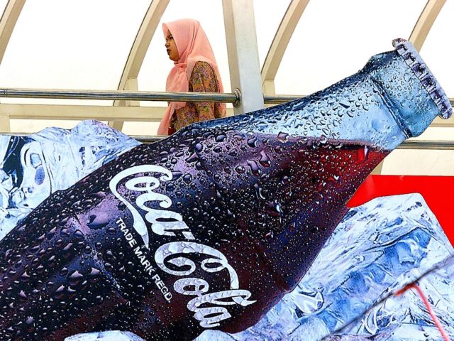 A woman walks past a soft drink advertisement billboard in Kuala Lumpur, 16 March 2003. Le