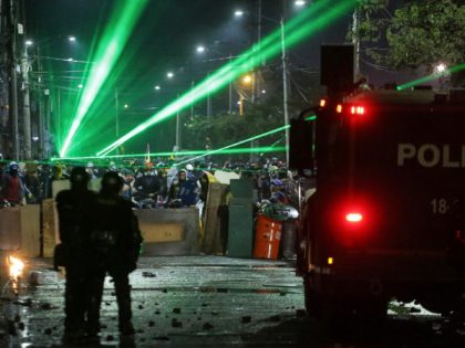 Anti-government protesters point lasers at police during clashes in Bogota, Colombia, Friday, May 21, 2021. Colombians have taken to the streets for weeks across the country after the government proposed tax increases on public services, fuel, wages and pensions. (AP Photo/Ivan Valencia)