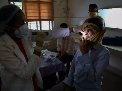 An Indian doctor checks a man who recovered from COVID-19 and now infected with black fung