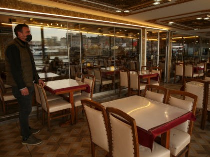A man stands in an empty restaurant, in Istanbul, Tuesday, April 13, 2021. As Muslims arou