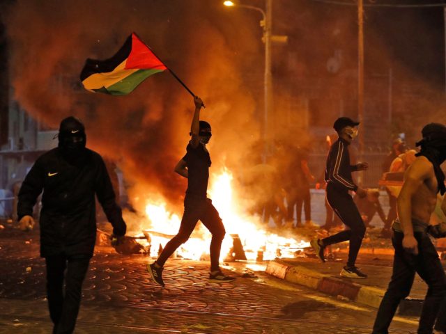 TOPSHOT - Palestinian protesters hurl stones during clashes with Israeli forces in the Shuafat Palestinian neighbourhood, neighbouring the Israeli settlement of Ramat Shlomo, in Israeli-annexed east Jerusalem on May 14, 2021. - Israel faced a widening conflict, as deadly violence escalated across the West Bank amid a massive aerial bombardment …