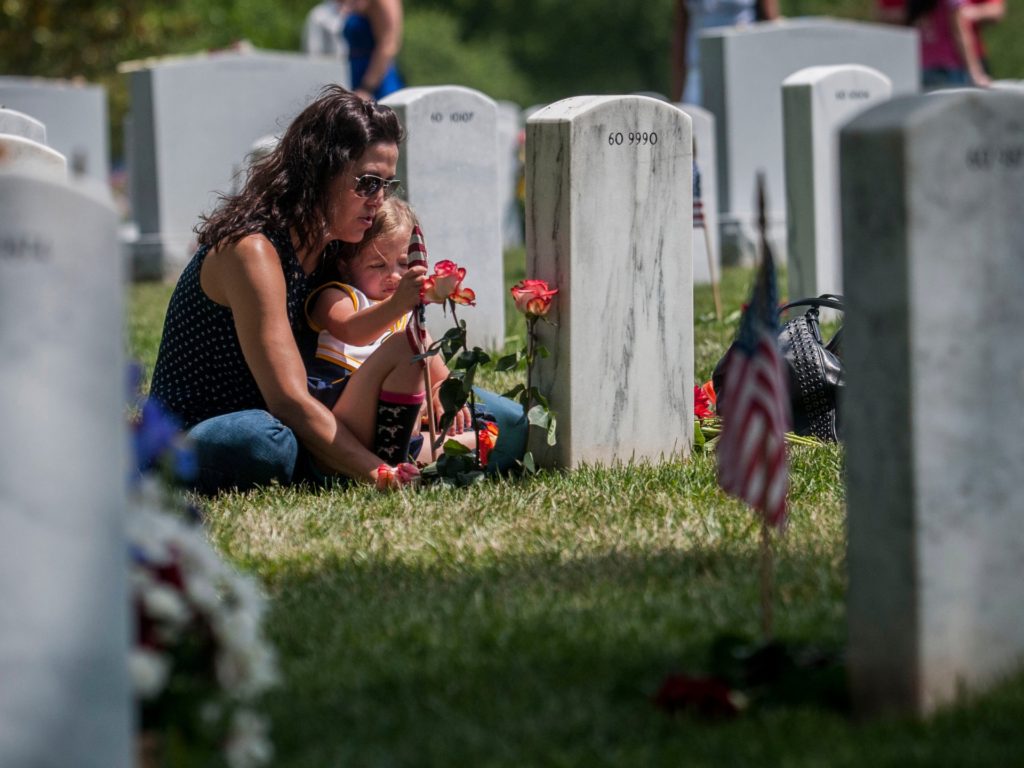 ARLINGTON, VA - MAY 25: Angela Spraul and her daughter Ava, 4, sit at the grave of her husband John Spraul, U.S. Navy, who died Feb. 28, 2013, at Section 60 on Memorial Day at Arlington National Cemetery on May 25, 2015 in Arlington, Va. U.S. President Barack Obama, Chairman of the Joint Chiefs of Staff U.S. Army General Martin Dempsey and U.S. Defense Secretary Ash Carter honored fallen soldiers during a ceremony at Arlington on this Memorial Day. (Photo by Gabriella Demczuk/Getty Images)
