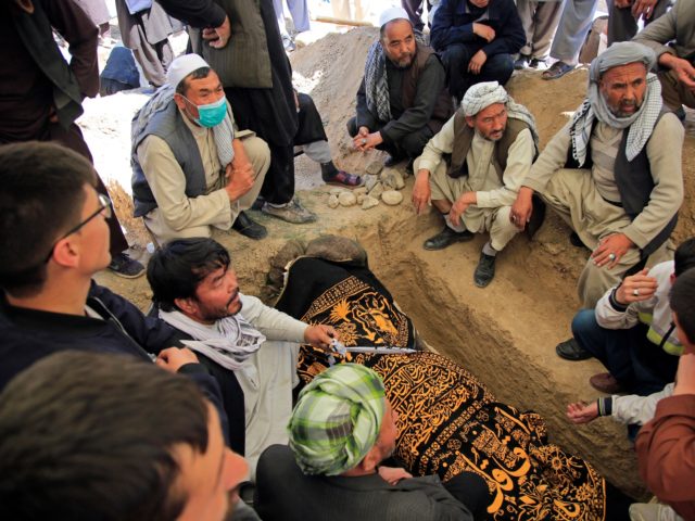 Afghan men bury a victim of deadly bombings on Saturday near a school, at a cemetary west