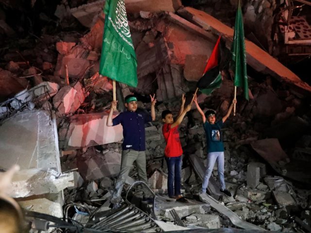 Palestinian children wave green Hamas and their national flags as they stand on the rubble