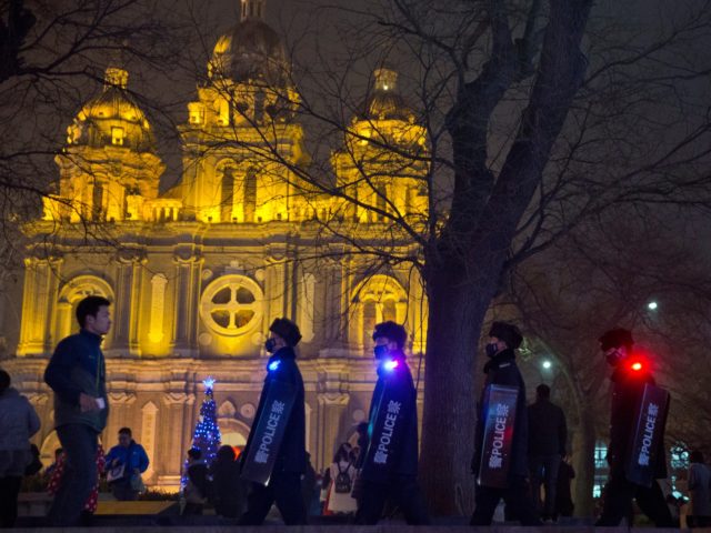 Police officers with shields march past the Dongtang Catholic church in Beijing, China, Thursday, Dec. 24, 2015. Beijing police announced Thursday that they had issued a yellow security alert to ensure safety during the Christmas period. (AP Photo/Ng Han Guan)